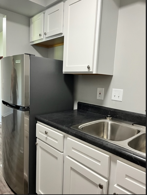 a kitchen with white cabinets and a stainless steel refrigerator