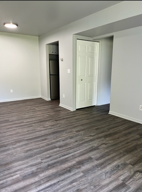 an empty living room with wood flooring and a white door