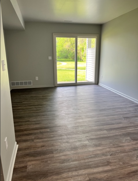 an empty living room with wooden floors and a sliding glass door