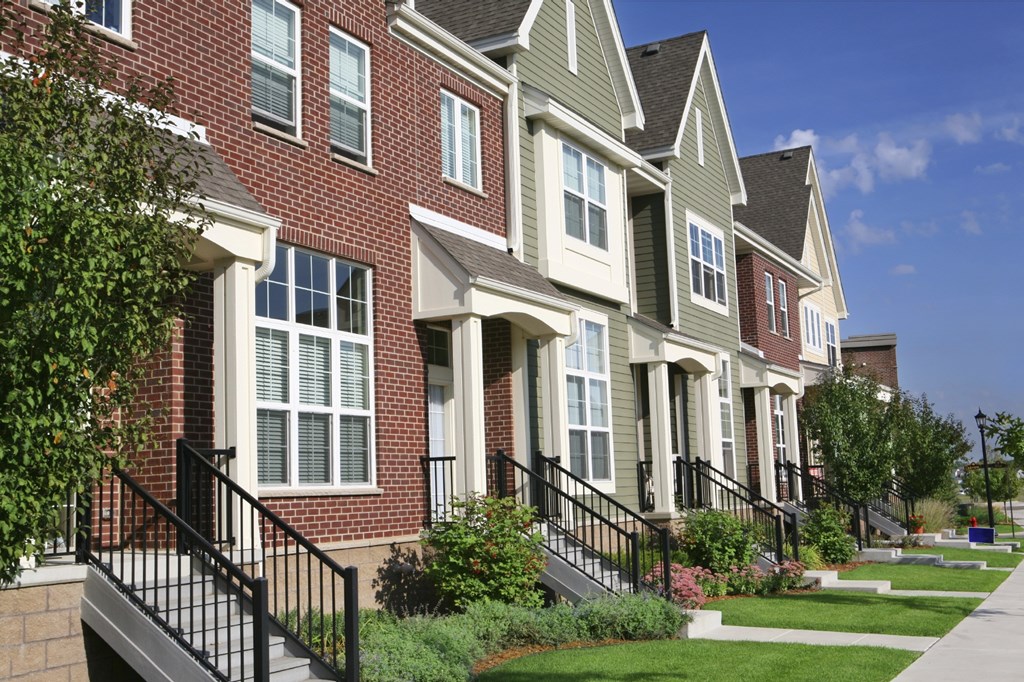 a row of townhouses with stairs and grass in front of them