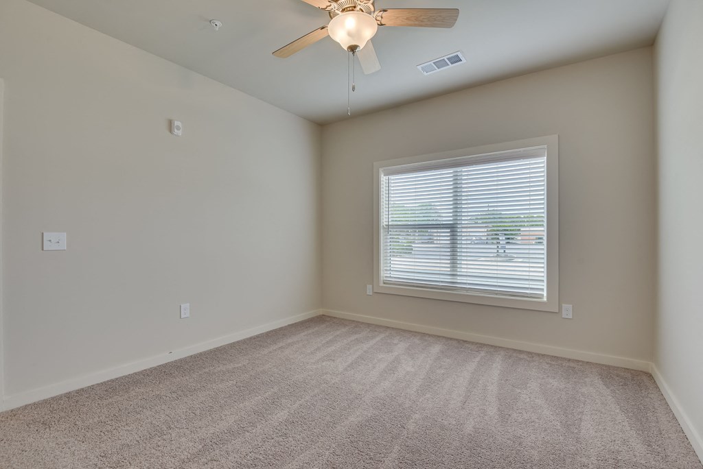 an empty living room with a ceiling fan and a window