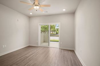 an empty living room with a ceiling fan and a door to a patio at The Augustan, Augusta, Georgia