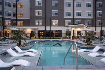 a swimming pool with white chairs in front of a building at The Augustan, Augusta, Georgia