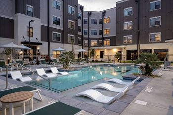 a swimming pool with lounge chairs in front of an apartment building at The Augustan, Georgia, 30901