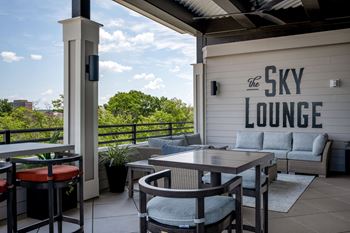 a patio with tables and chairs and a sky lounge sign at The Augustan, Augusta, GA