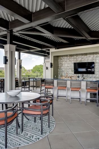 a patio with tables and chairs and a television at The Augustan, Augusta, GA