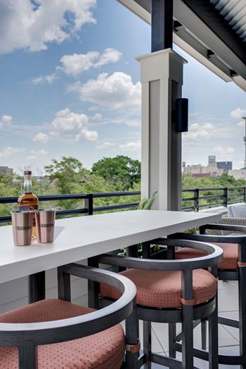 a balcony with a table and chairs and a bottle of whisky on it at The Augustan, Augusta, Georgia