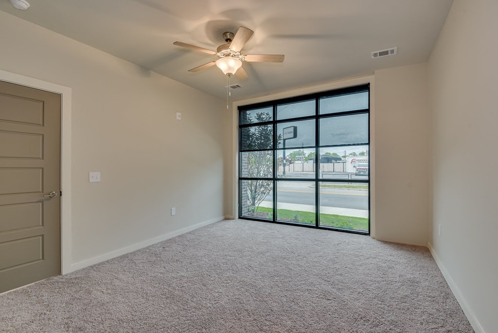 an empty bedroom with a large window and a ceiling fan