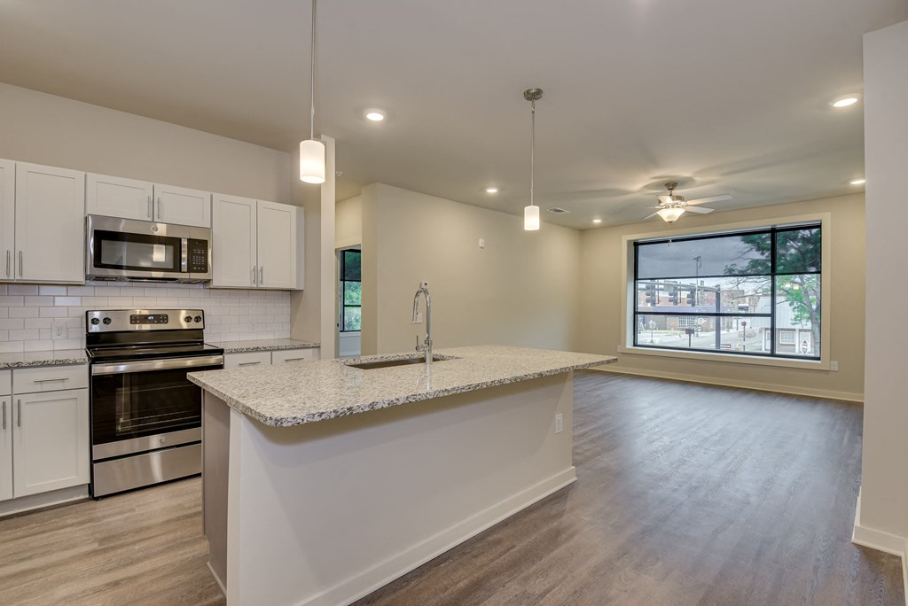 an open kitchen and living room with a granite counter top