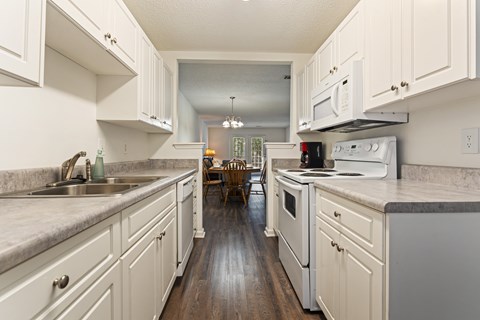 A kitchen with white cabinets and a wooden floor.