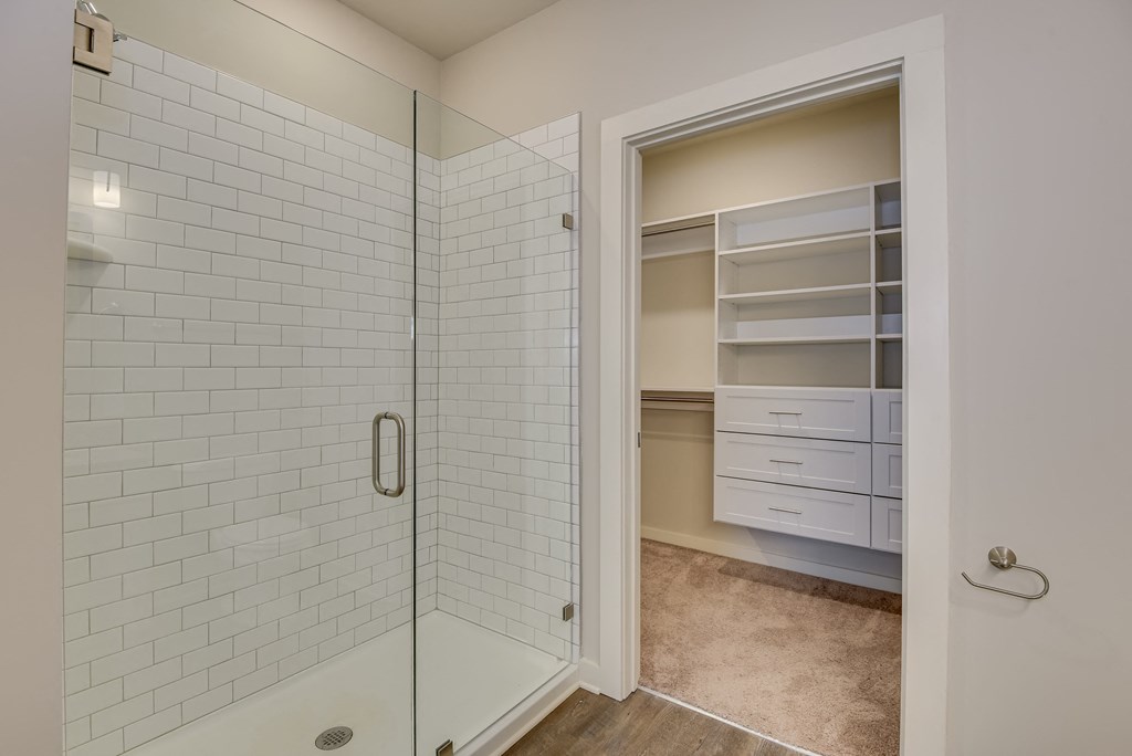 a white tiled bathroom with a shower and a closet