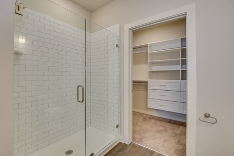 a white tiled bathroom with a shower and a closet at The Augustan, Augusta, Georgia
