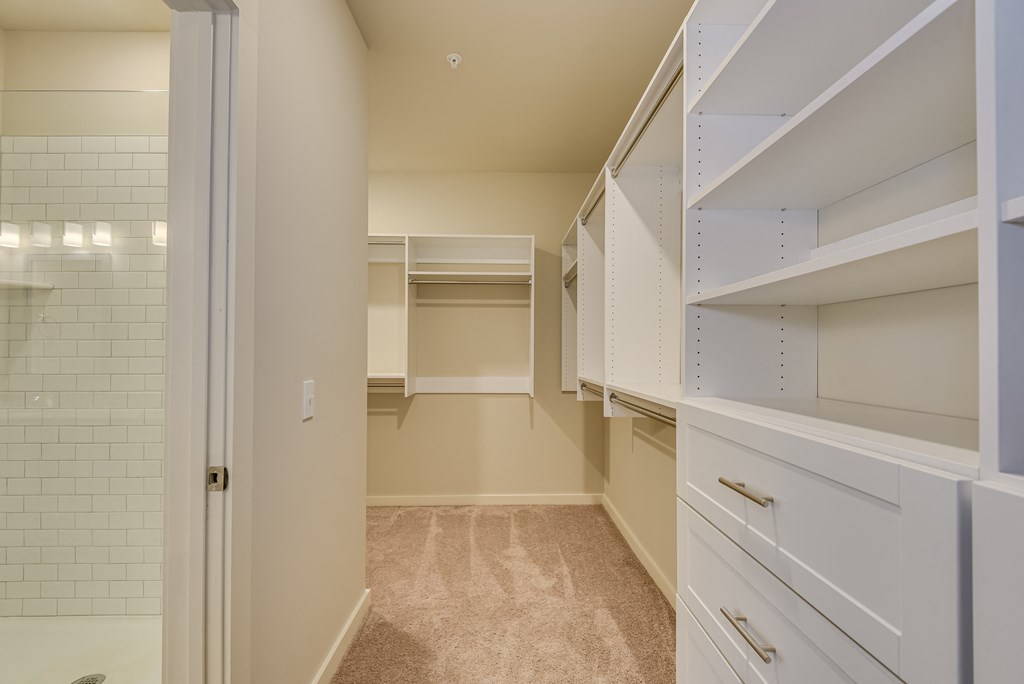 a walk in closet with white cabinets and a tiled floor