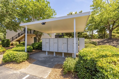 A white covered mailbox is situated in front of a house.