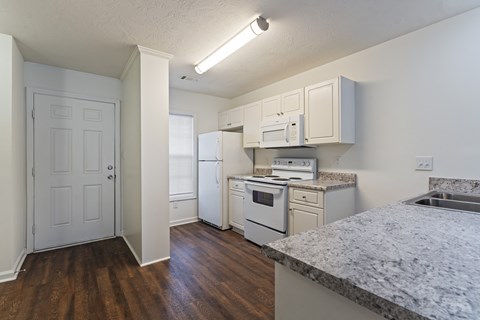 A kitchen with white appliances and wooden floors.