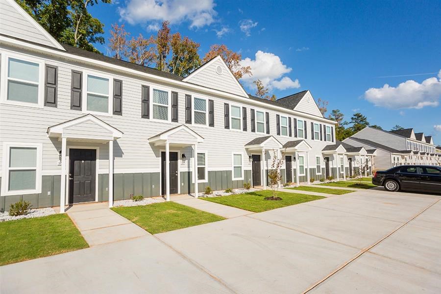a row of white houses with a car parked in front