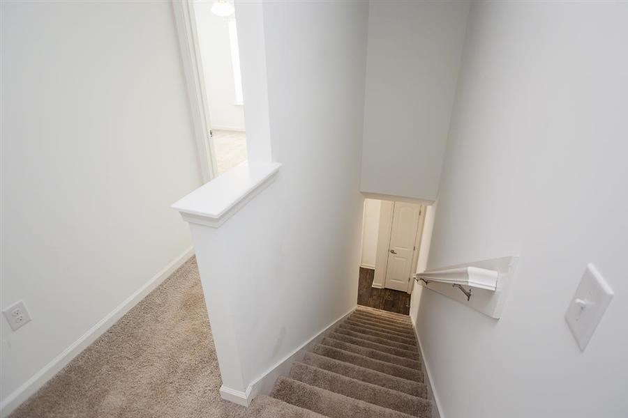 a staircase in a home with white walls and a window