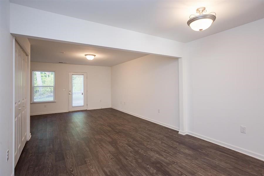 an empty living room with a wood floor and white walls