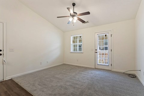 A room with a ceiling fan and carpeted floor.