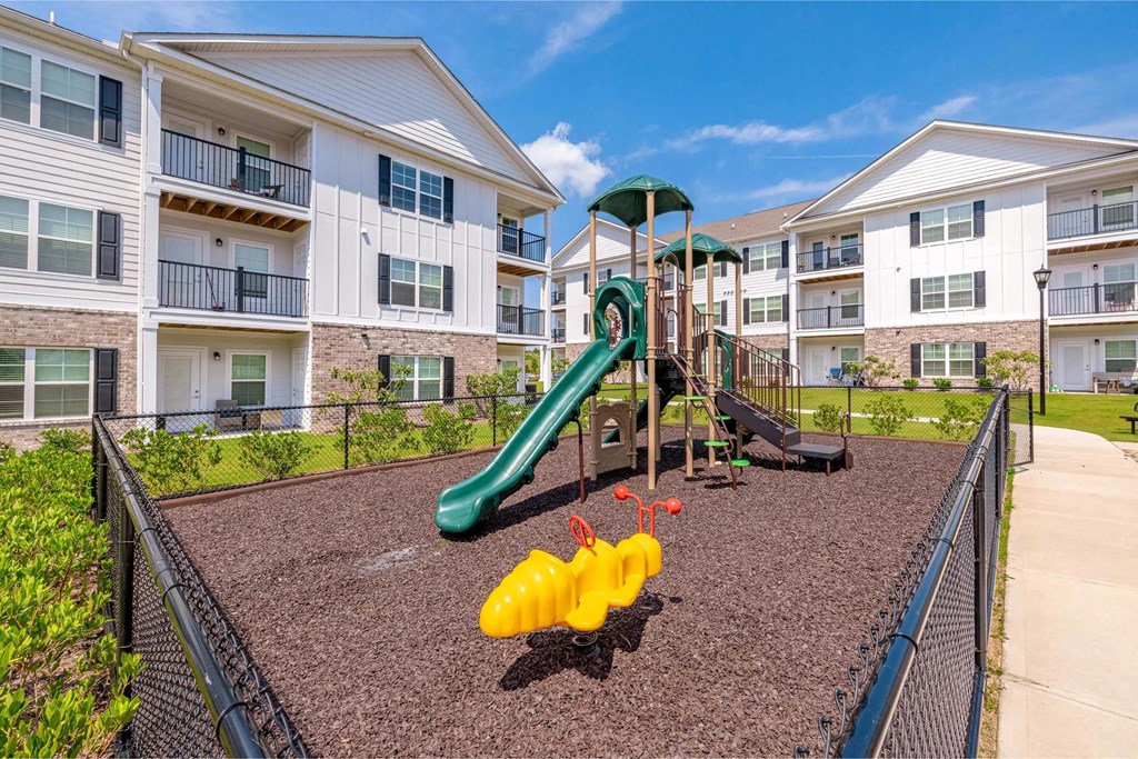 Playground with slide in fenced-in area with mulch