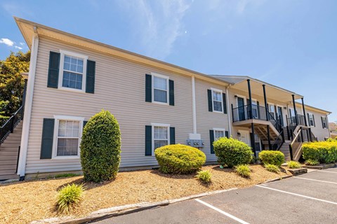 A beige house with black shutters and a balcony.
