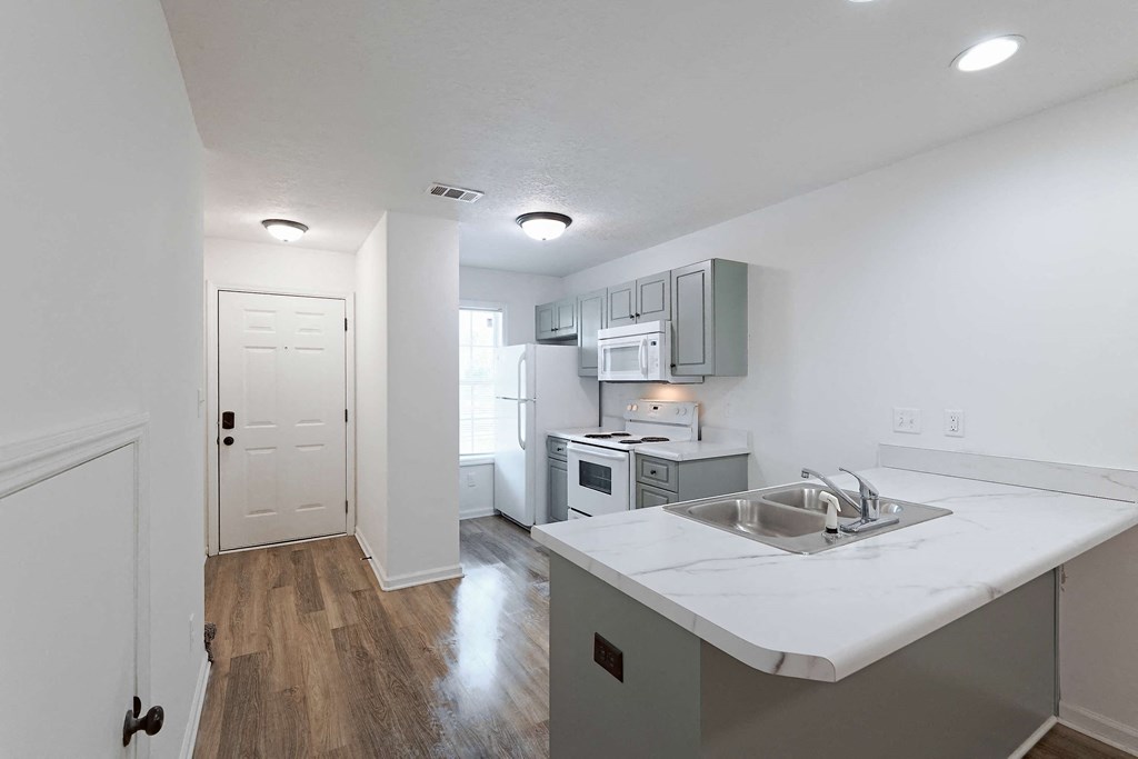 Kitchen area with white appliances and hallway leading to front door