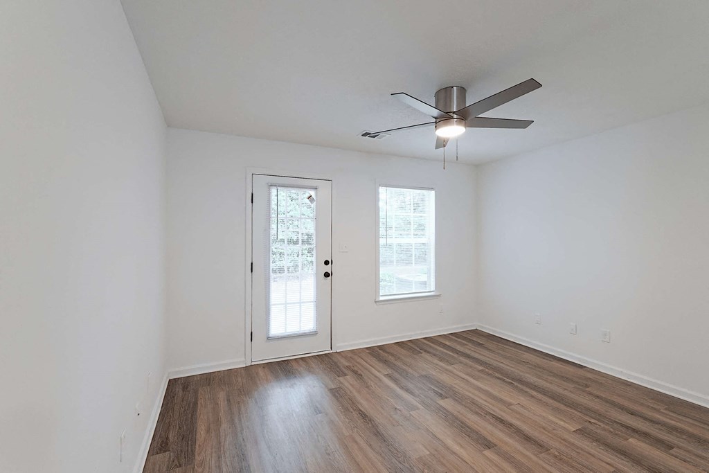 Living area with ceiling fan, hardwood-style flooring, and door to back patio area at Sterlington Apartments, Grovetown, GA