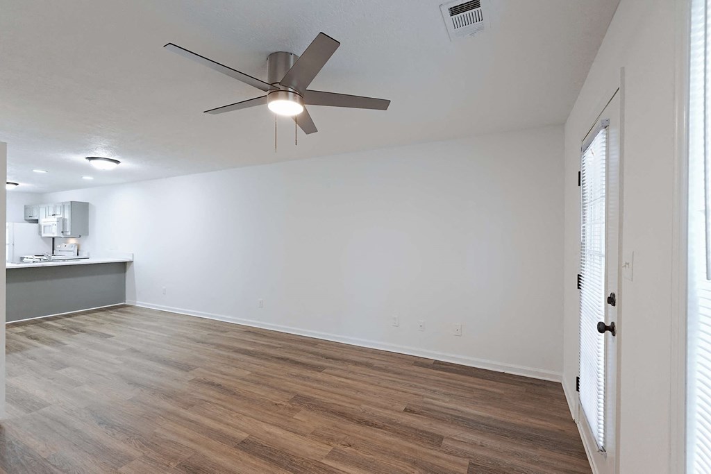 Living room with ceiling fan and hardwood-style LVT flooring at Sterlington Apartments, Georgia, 30813