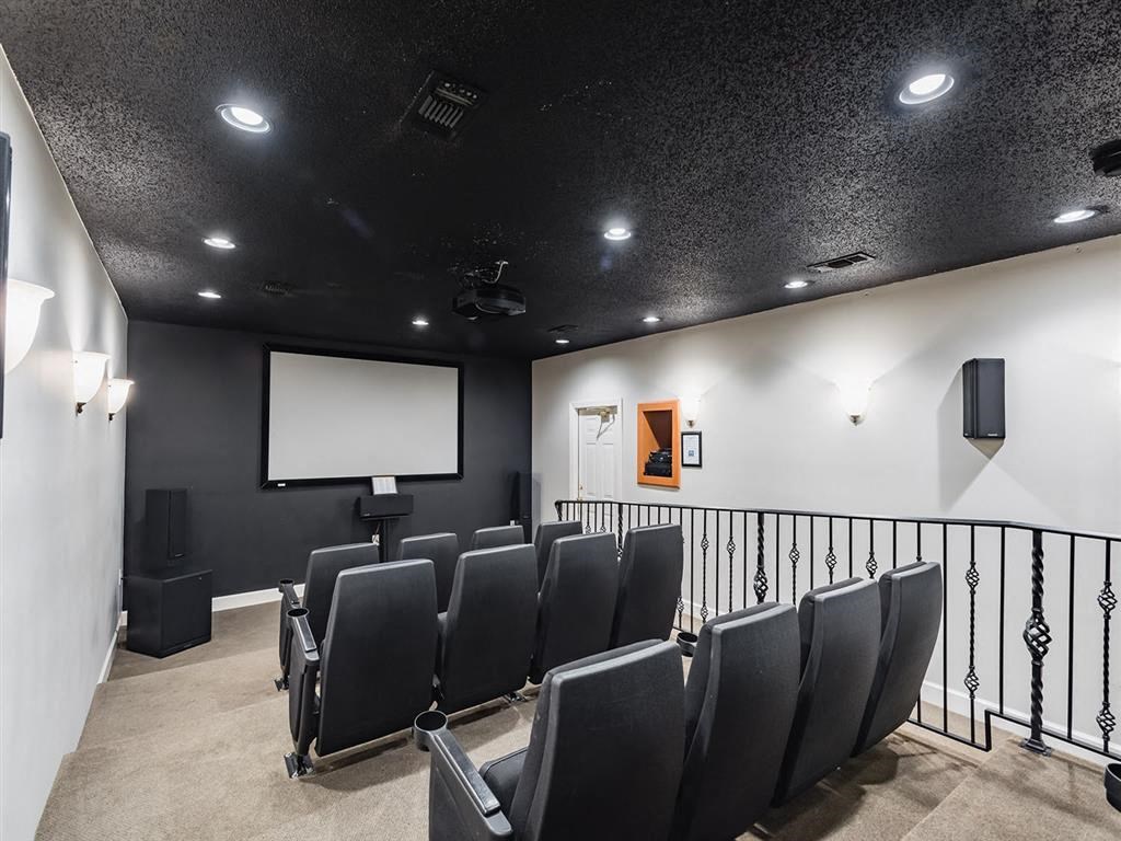 a large screening room with black chairs and a projector screen