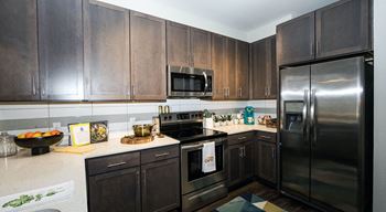 A kitchen with dark wood cabinets and stainless steel appliances at The Collective NoDa, Charlotte
