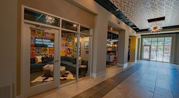 A hallway with a glass door leading to a room with a sign that says at The Collective NoDa, Charlotte