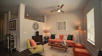 A living room with a green chair, a red ottoman, and a white wall with a circular design at The Collective NoDa, Charlotte