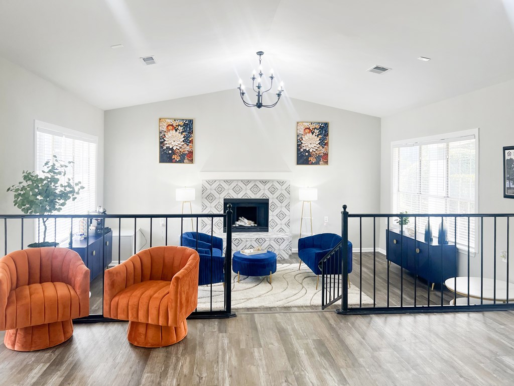 A living room with a fireplace, two orange chairs, and a blue chair.