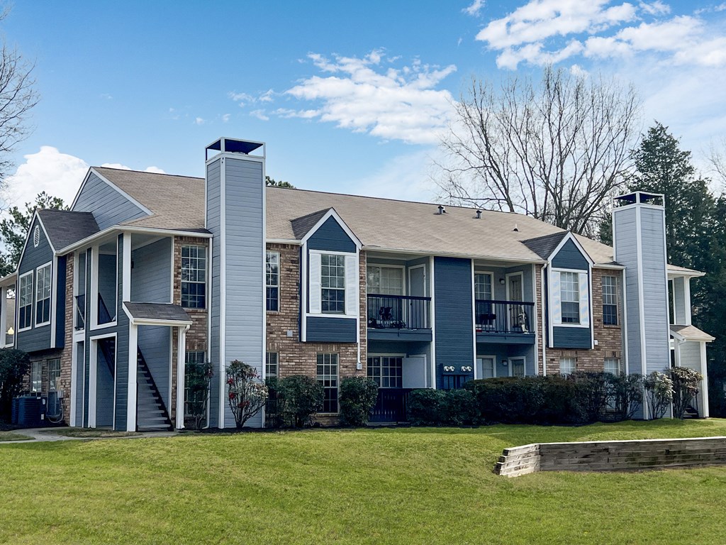 A large grey building with a balcony and a small tower on the right side.