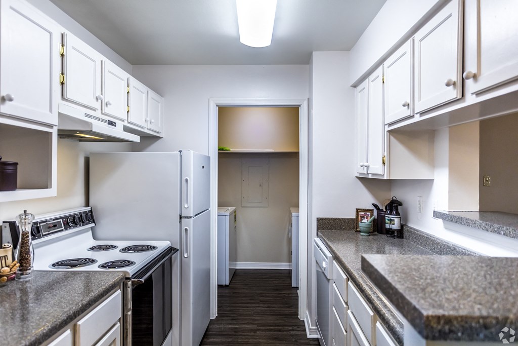 a kitchen with white cabinets and white appliances and granite counter tops