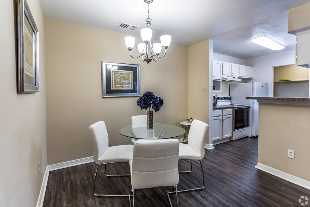 a dining room with a glass table and chairs and a kitchen