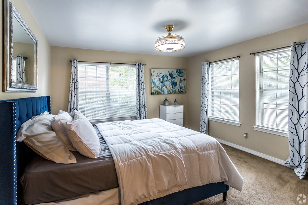 a bedroom with a bed and three windows