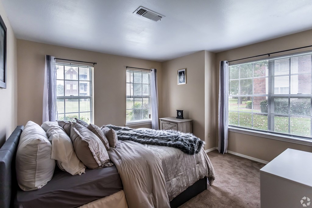 an empty bedroom with a bed and two windows