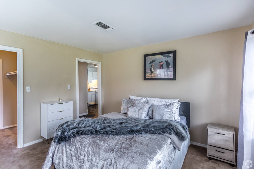 a bedroom with a bed and a dresser and a bathroom