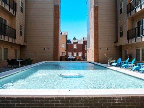 a swimming pool with blue chairs and a building in the background