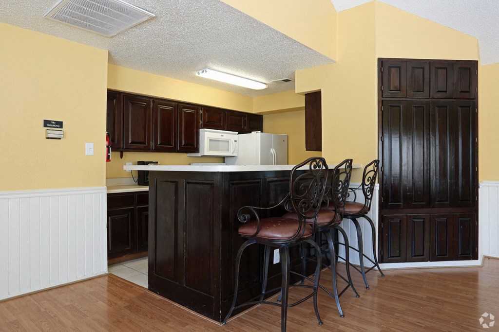 a kitchen with a bar with chairs and a refrigerator