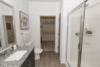 A bathroom with a walk in shower and a toilet at Cue Luxury Apartments, Cypress, Texas