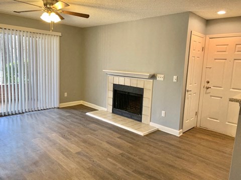 A living room with a fireplace and a ceiling fan.