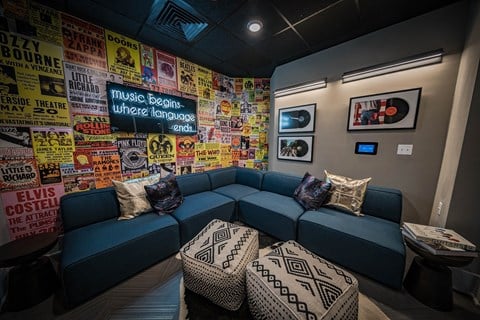 a living room with a blue couch and pillows and a wall covered in posters