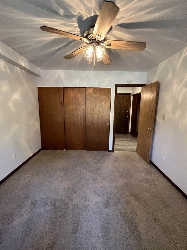 an empty living room with a ceiling fan and a closet