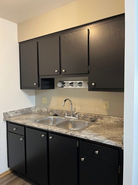 A kitchen with black cabinets and a granite countertop.