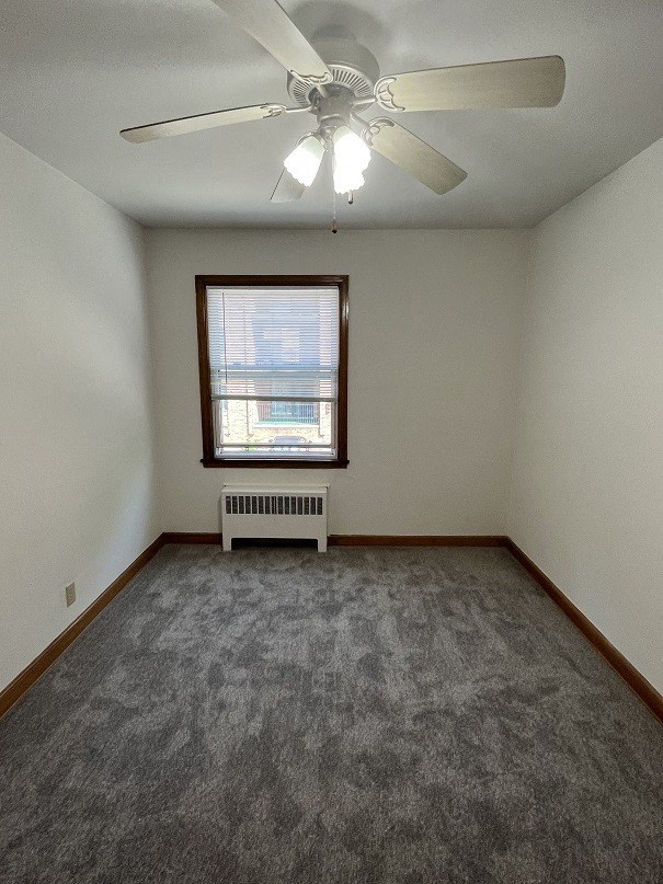 an empty living room with a ceiling fan and a window