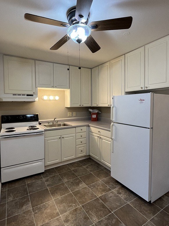 a kitchen with white appliances and a ceiling fan