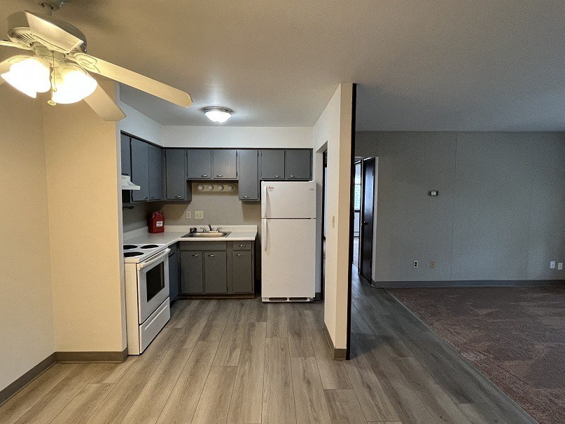 a kitchen and living room with a white refrigerator and stove