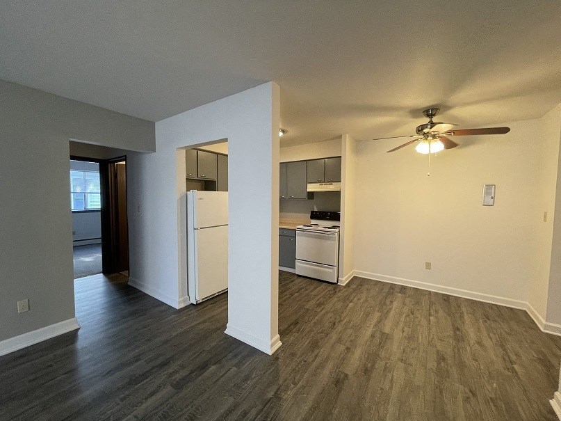 an empty living room and kitchen with a ceiling fan